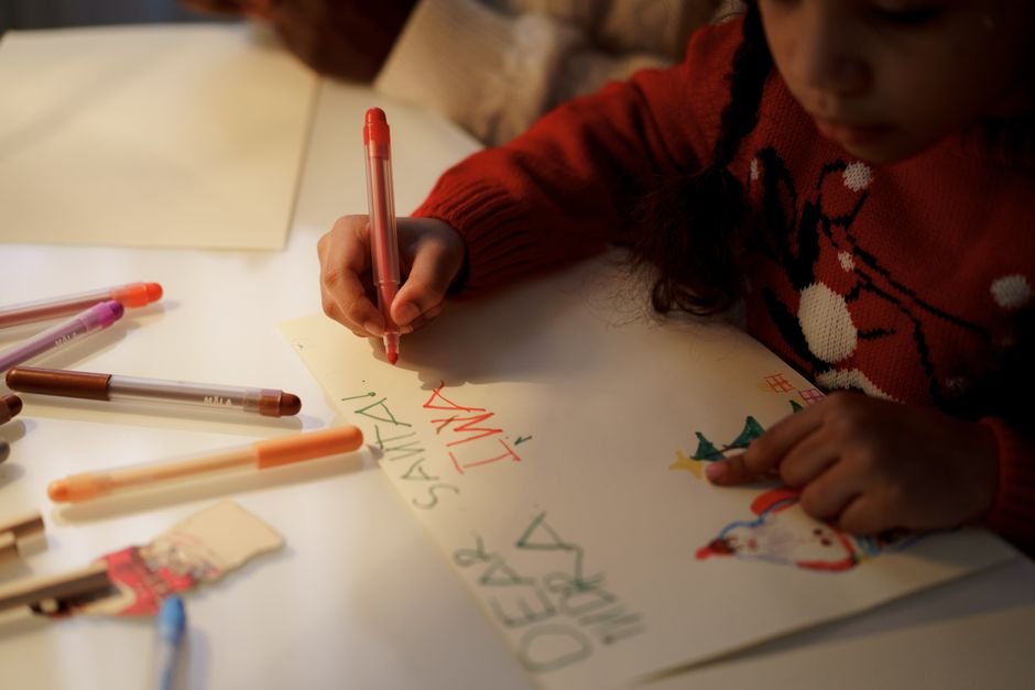 Niña escribiendo la carta a Papá Noel en casa como ritual de la cuenta atrás navideña