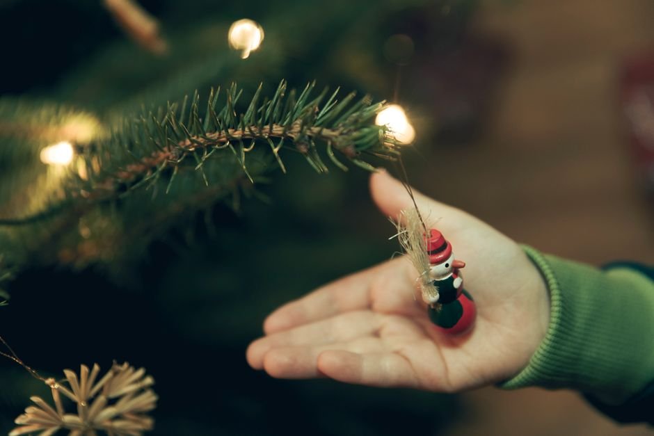 Niño colgando en el árbol su bola de Navidad personalizada con su nombre