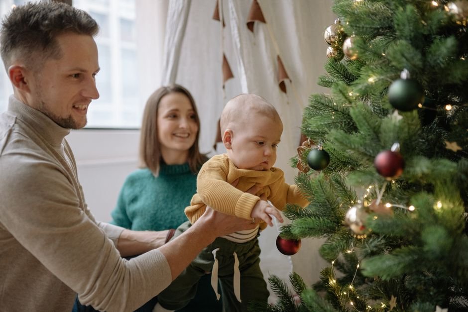 Bebé en su primera Navidad junto al árbol, un momento ideal para un adorno con su nombre y el año
