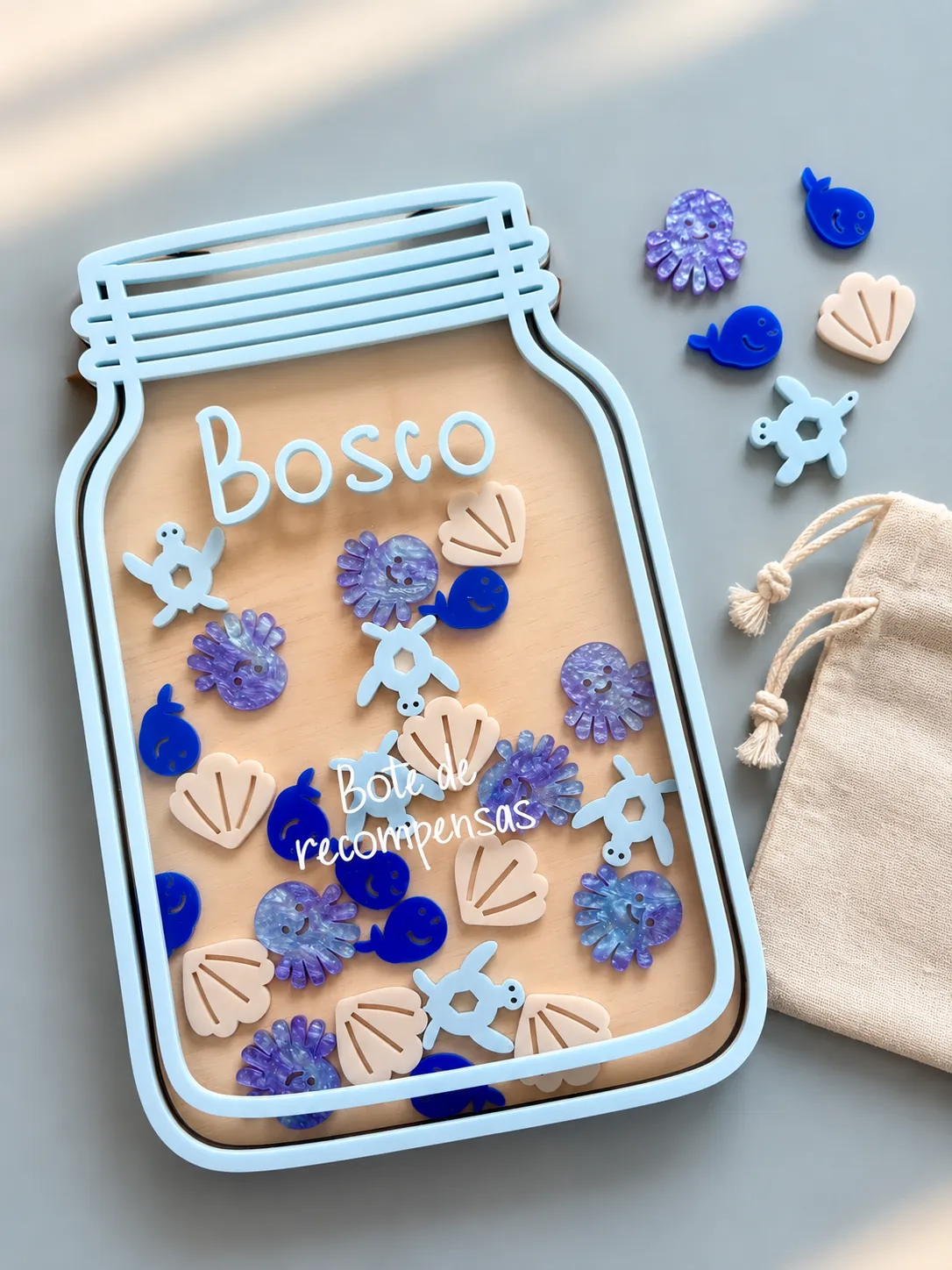 Bote de recompensas de madera personalizado con el nombre Bosco en azul cielo y fichas de tortugas, pulpos, ballenas y conchas, con su bolsita de tela