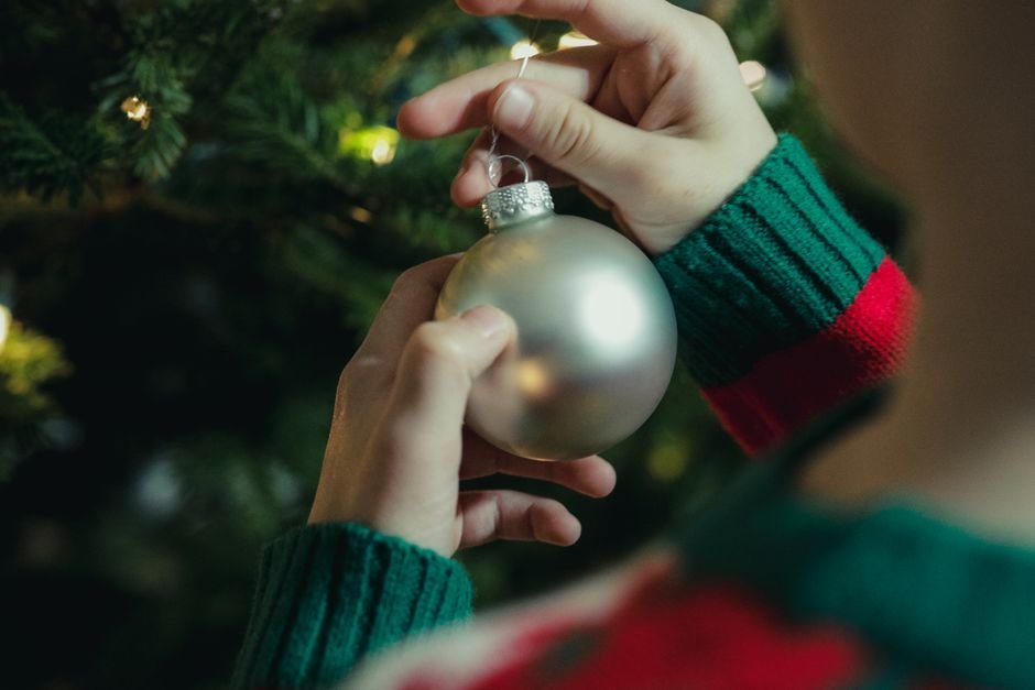 Niño colgando su bola de Navidad personalizada con nombre en el árbol familiar